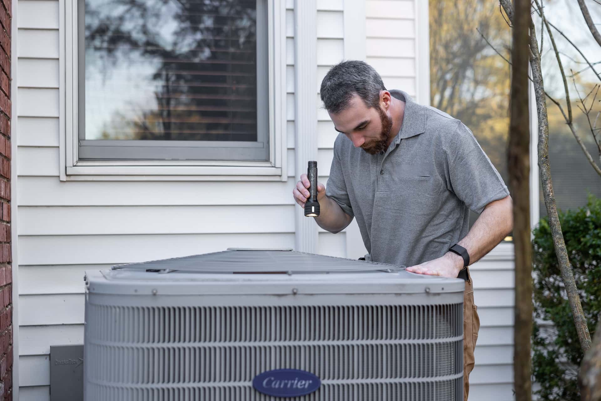 An HVAC technician checking an outdoor unit on a Dallas-Fort Worth service call